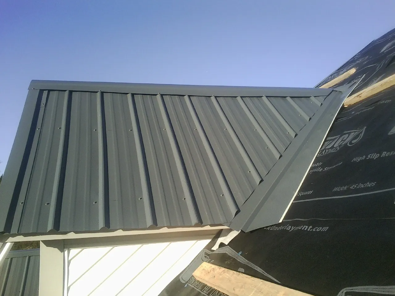 Gray metal roof panels going on over a garage gable in Joseph
