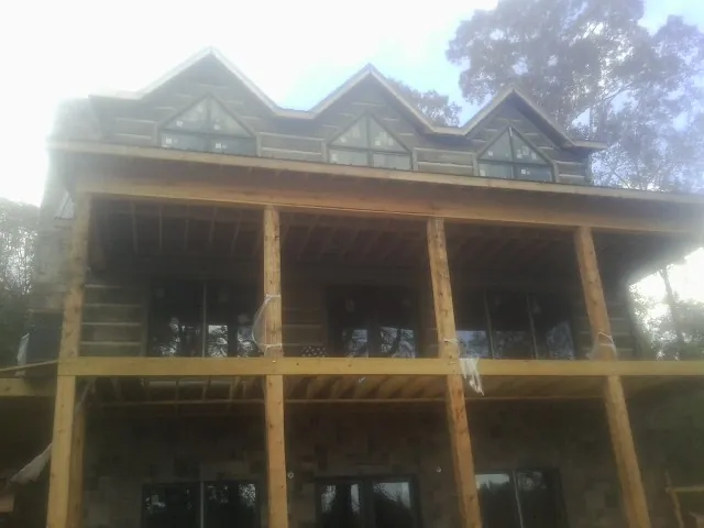Dormers and porch framing on a large log home under construction — Roof Coating work by our crew in Joseph