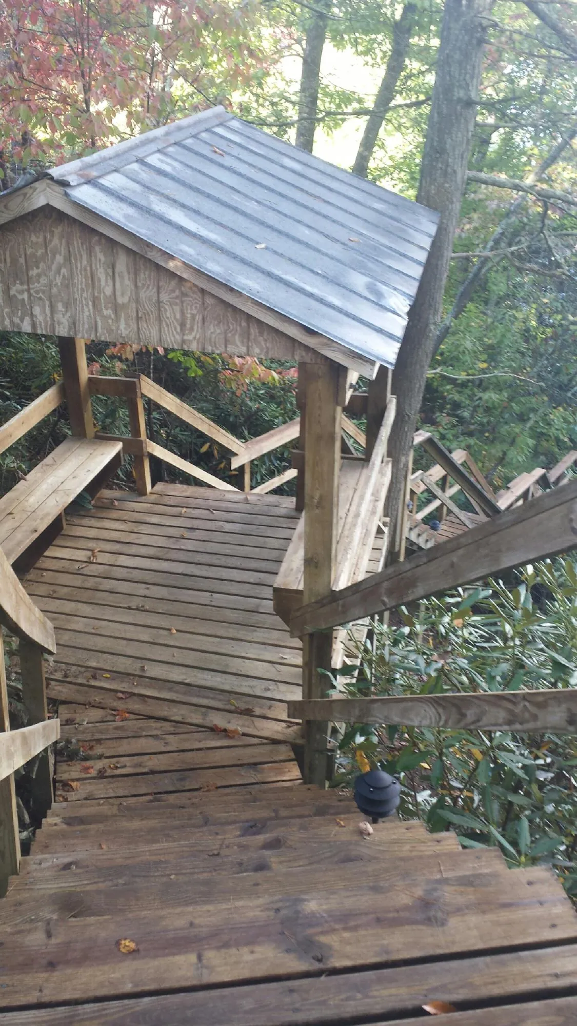 Metal roofed shelter over wooden steps on a wooded walkway — Skylight Repair & Installation work by our crew in Joseph